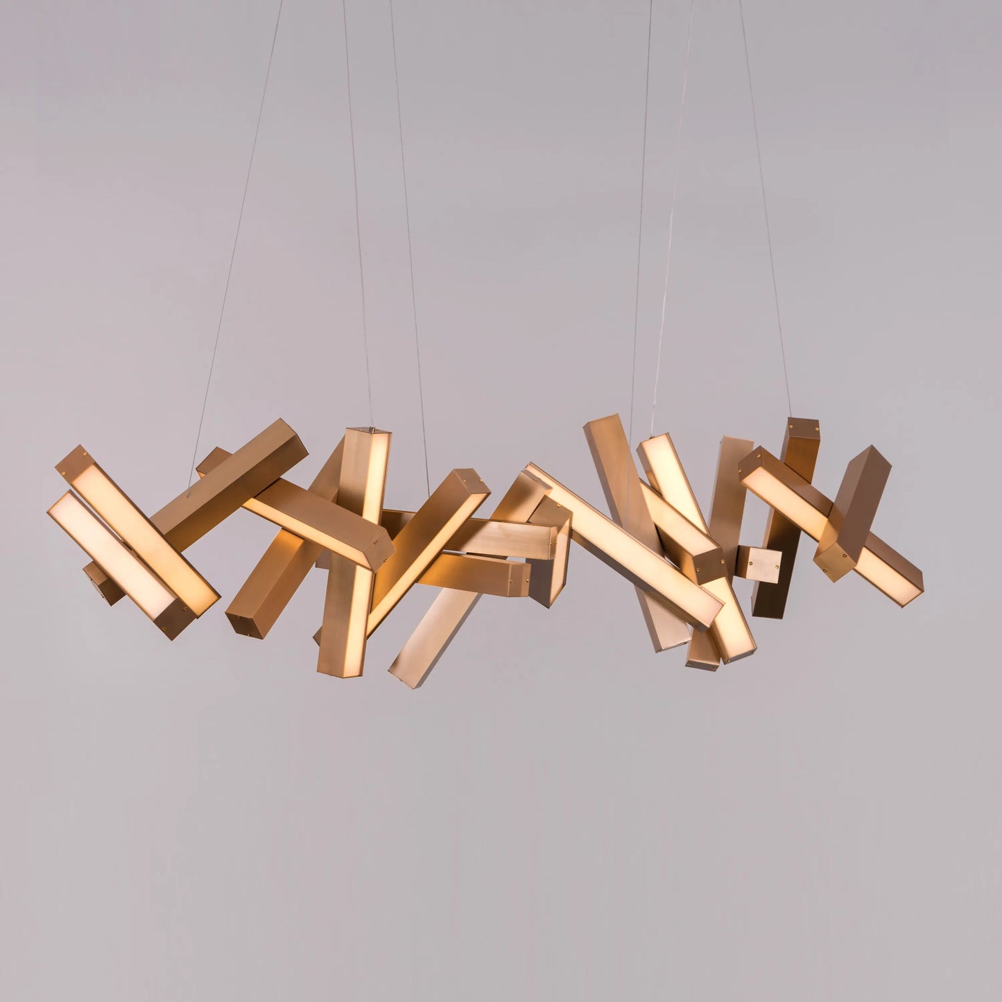 Large "Glow Miles" gold chandelier with multiple LED light sources, dramatically illuminated in a spacious, modern room.