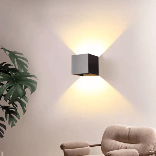 Sleek white minimalist wall sconce with a cylindrical shape, casting a soft glow on a neutral-toned wall, exemplifying clean design and functional lighting