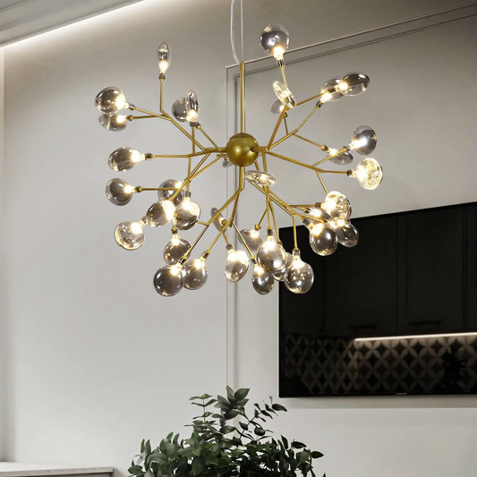 A gold, round chandelier with 27 branches tipped with LED bulbs hangs from a beach villa ceiling.