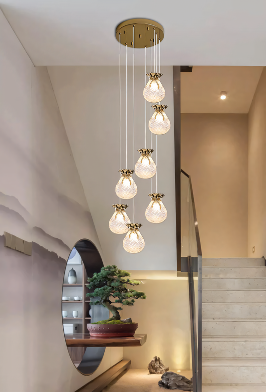 Elegant brass and crystal 6-light LED chandelier cascading down a tall staircase in a modern, luxury home interior