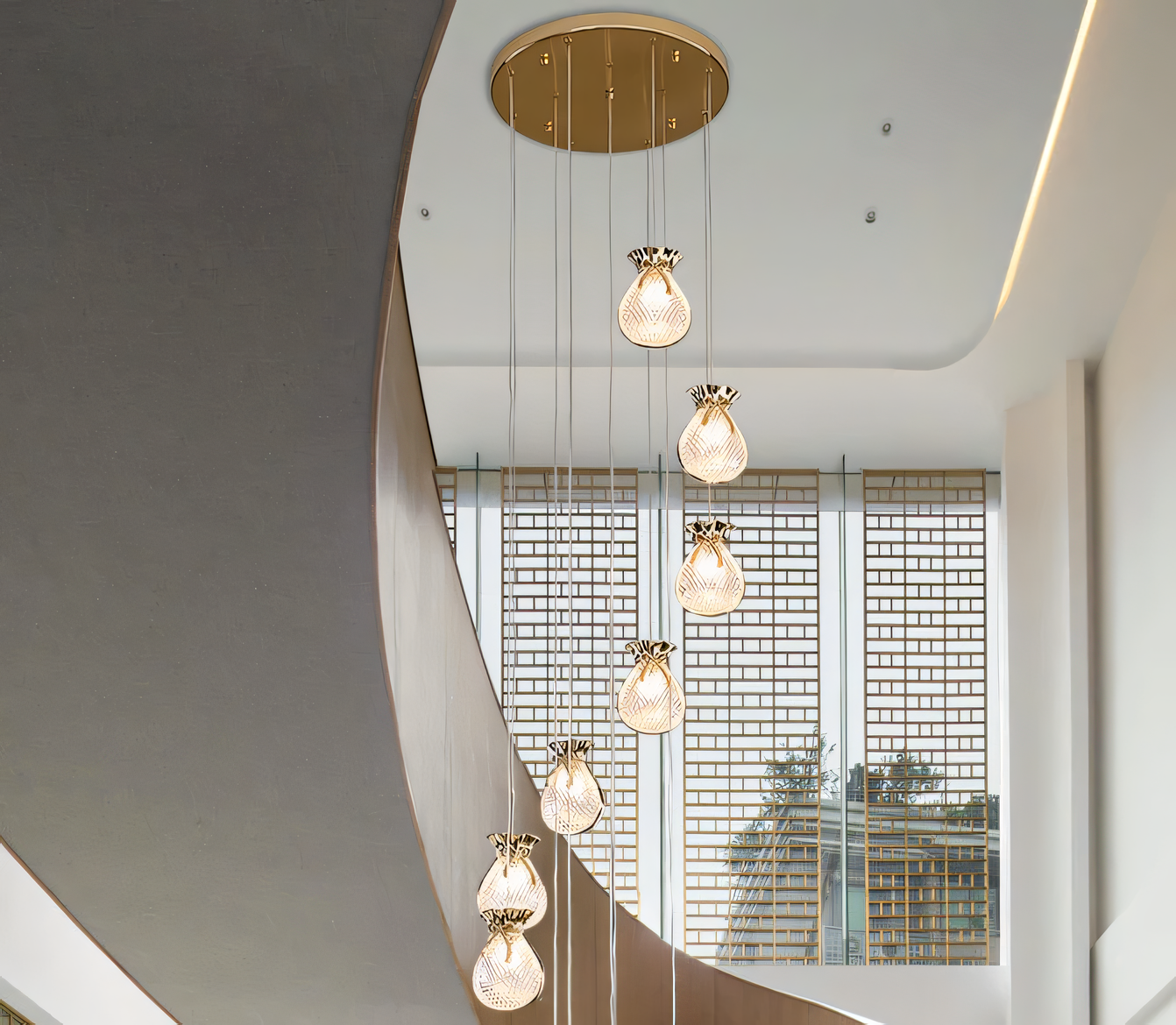 Elegant brass and crystal 6-light LED chandelier cascading down a tall staircase in a modern, luxury home interior