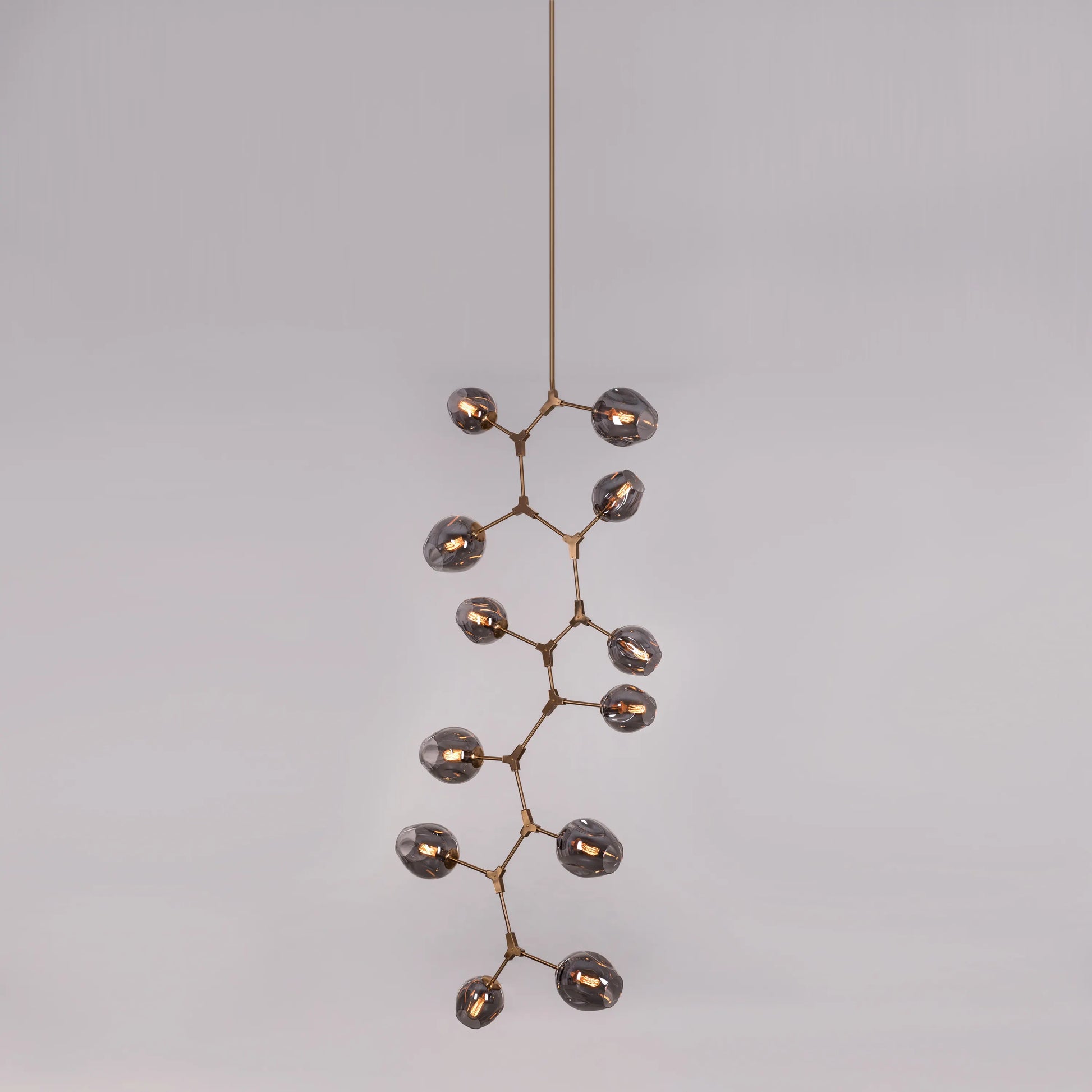 Close-up of the smokey grey glass heads and gold frame on the Twist In The Tale chandelier.