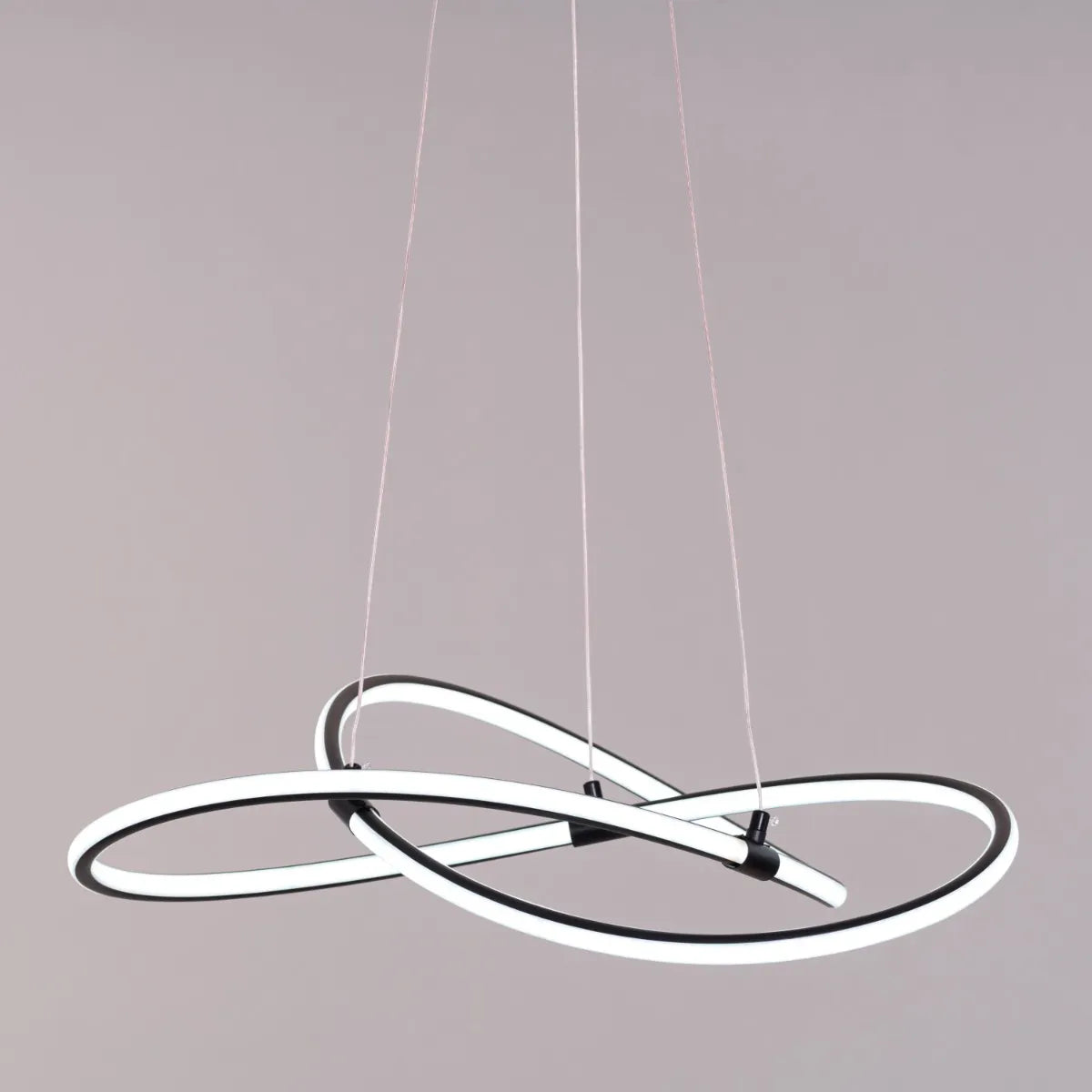 Black "Twist Of Fate" chandelier with intricate curved design, illuminated with warm white light.