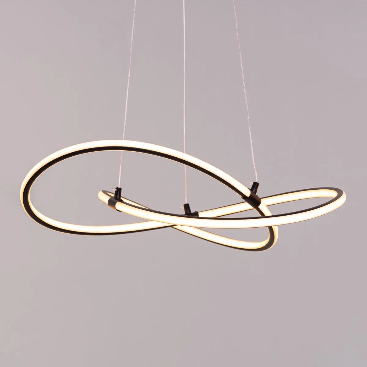 Black "Twist Of Fate" chandelier with intricate curved design, illuminated with warm white light.