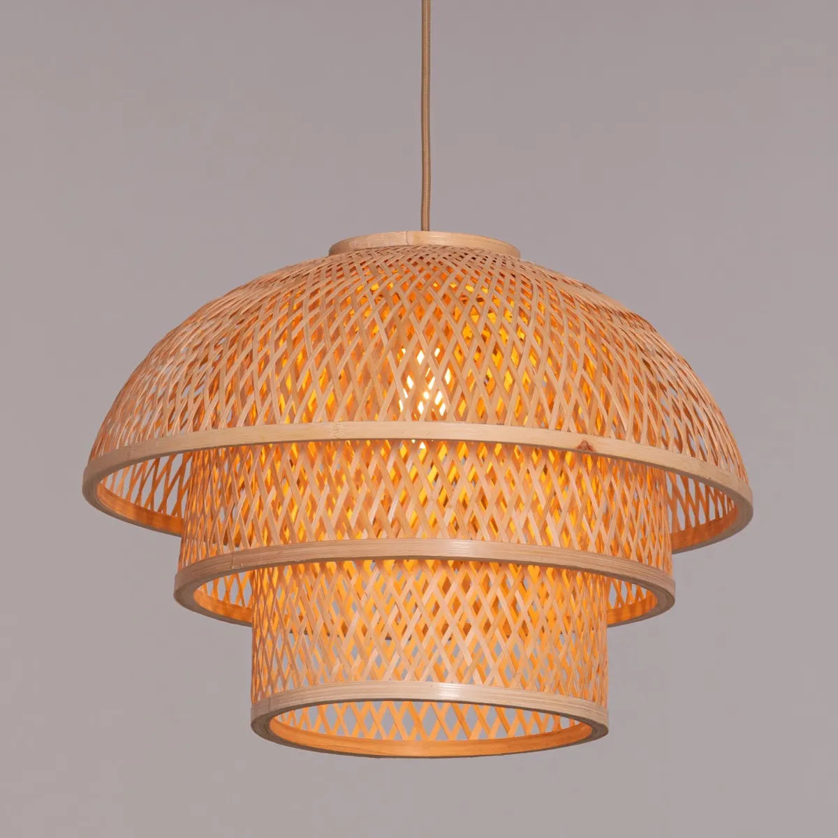 A unique rattan pendant light named 'Never The Same,' featuring a handcrafted, woven rattan shade with an organic, irregular shape. The natural fibers create a warm, inviting glow as light filters through the intricate patterns, offering a bohemian, rustic charm that adds texture and character to any space.