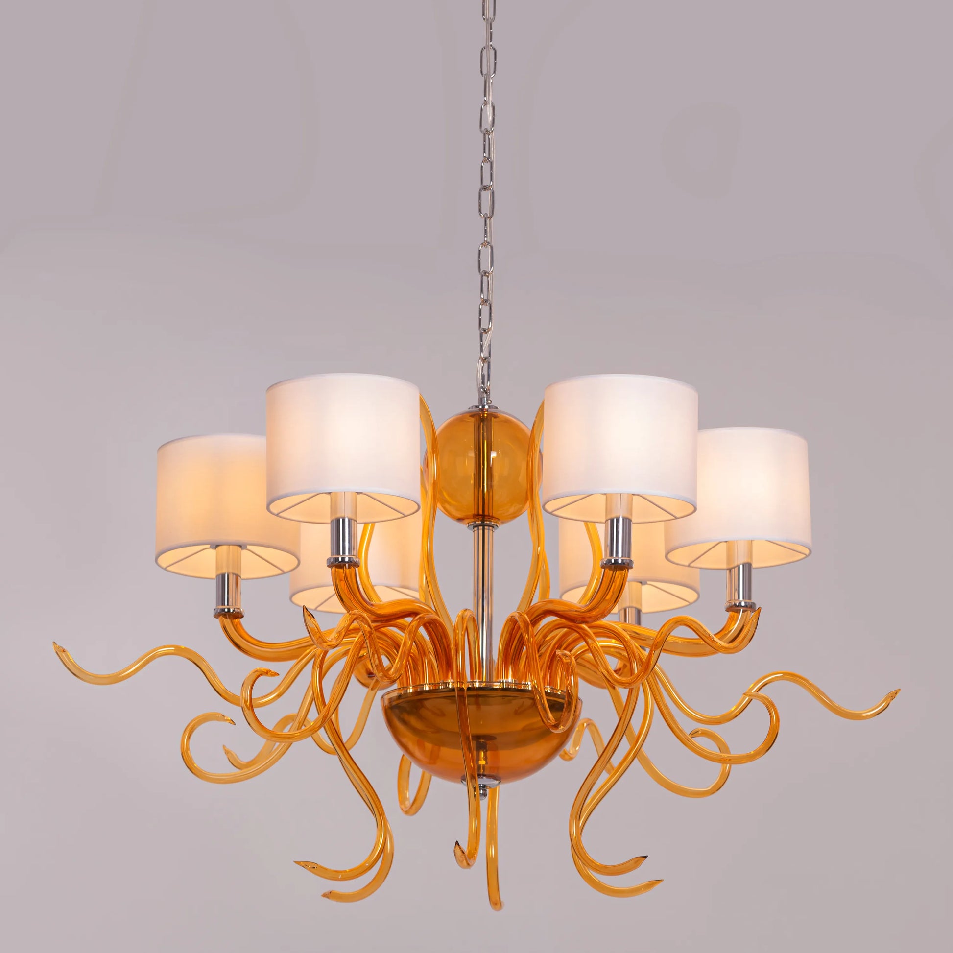 Large clear glass chandelier with chrome, amber, and white elements suspended in harmonious arrangement