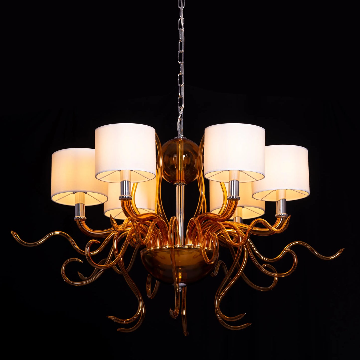 Large clear glass chandelier with chrome, amber, and white elements suspended in harmonious arrangement