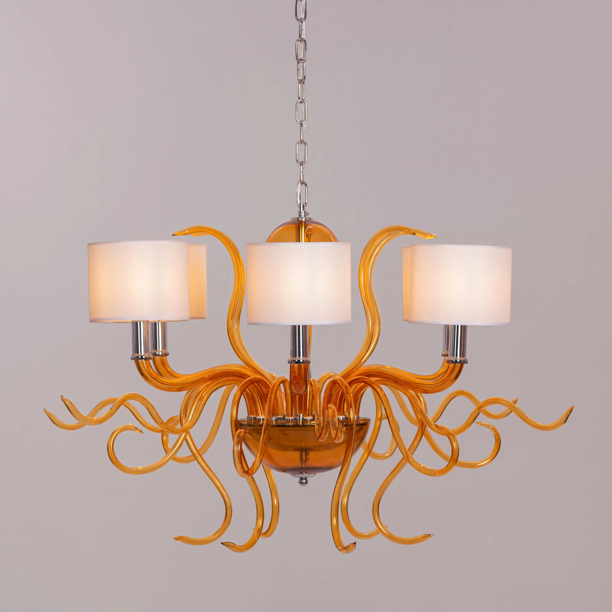 Large clear glass chandelier with chrome, amber, and white elements suspended in harmonious arrangement