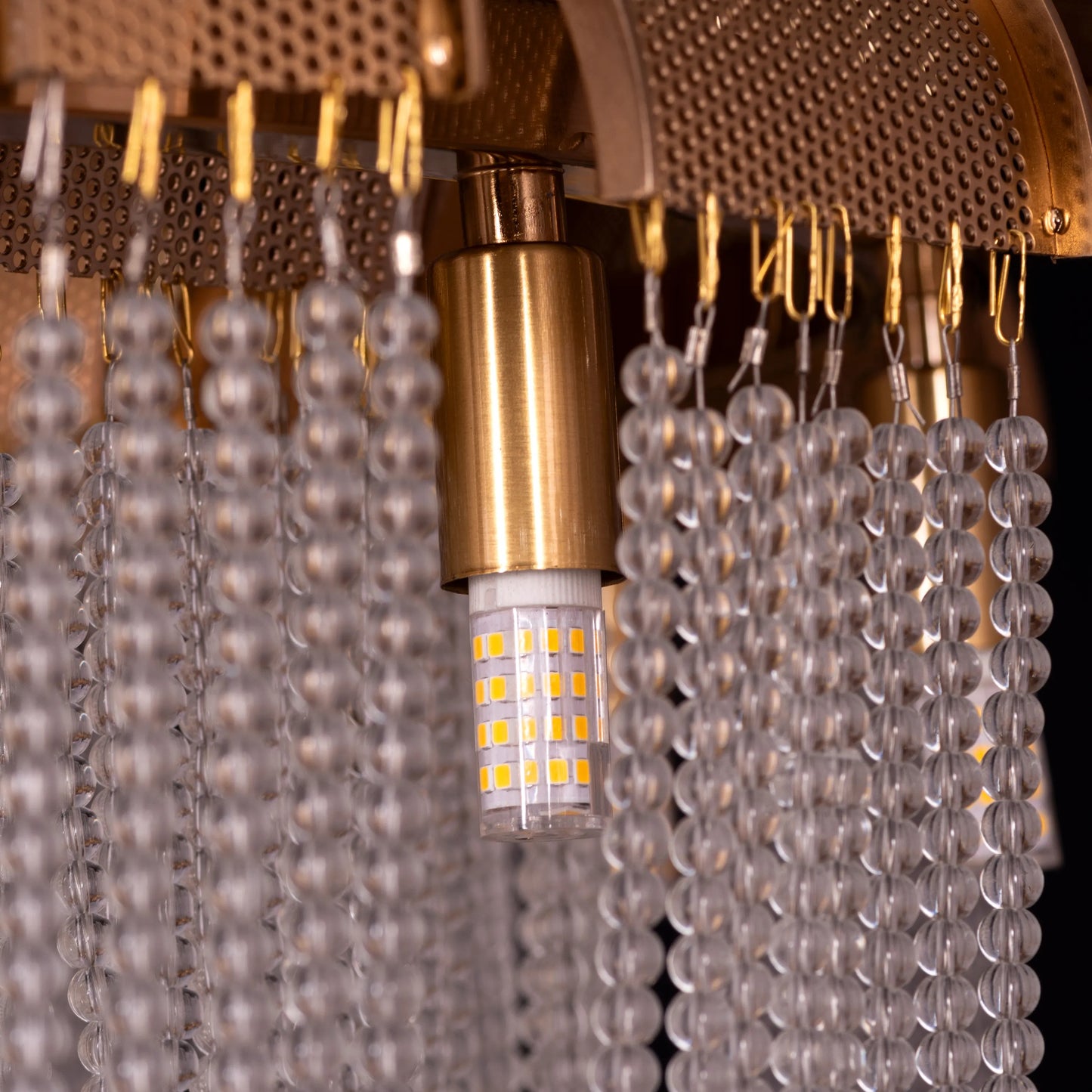 Medium-sized "Waves For Days" gold crystal chandelier with cascading tiers, illuminated and hanging in an elegant room.