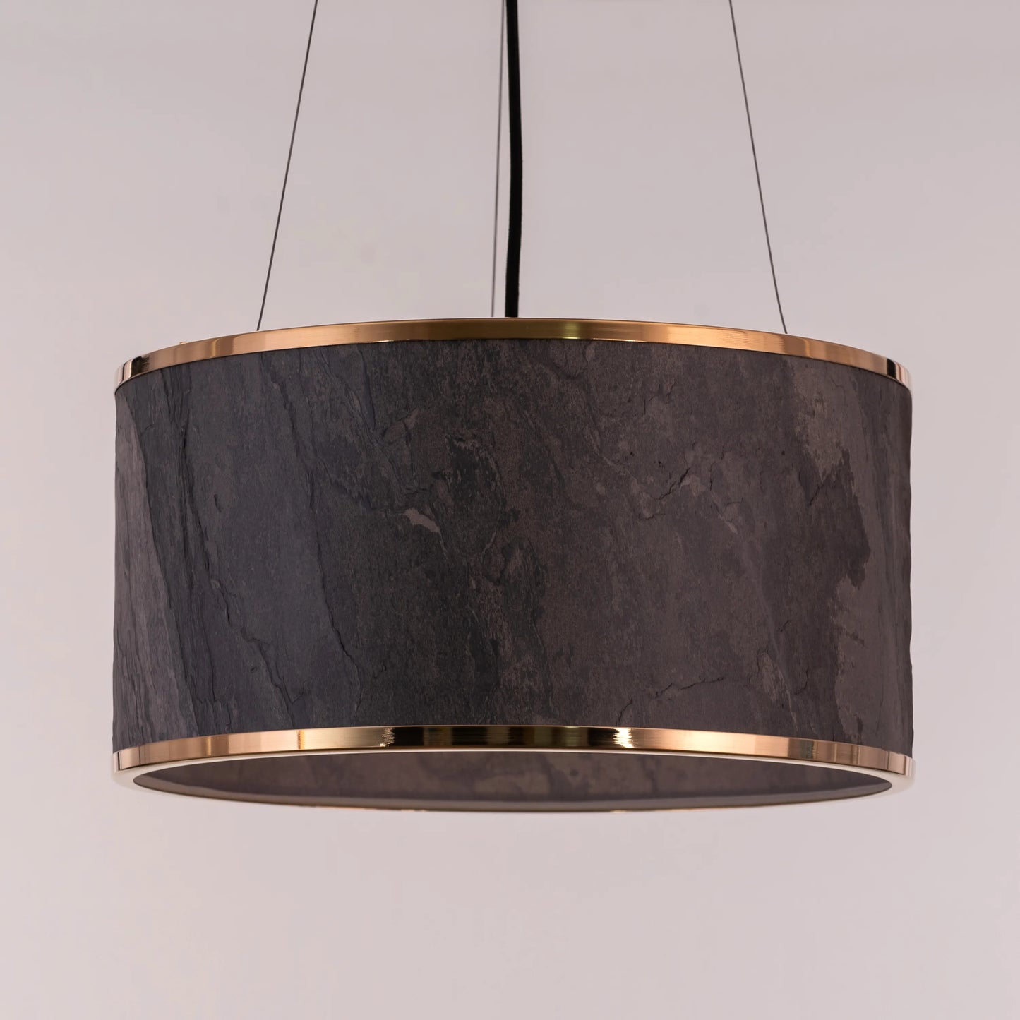 A contemporary pendant light named 'Touch & Glow,' featuring a striking gold stone veneer shade. The light's sleek design showcases the natural texture of the stone, beautifully reflecting and diffusing light to create a warm, inviting ambiance. This pendant light adds a touch of luxury and sophistication, making it an ideal choice for modern interiors.