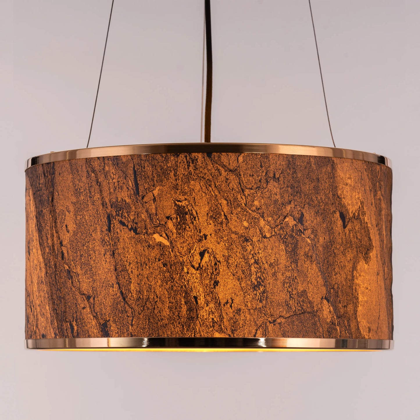 A contemporary pendant light named 'Touch & Glow,' featuring a striking gold stone veneer shade. The light's sleek design showcases the natural texture of the stone, beautifully reflecting and diffusing light to create a warm, inviting ambiance. This pendant light adds a touch of luxury and sophistication, making it an ideal choice for modern interiors.