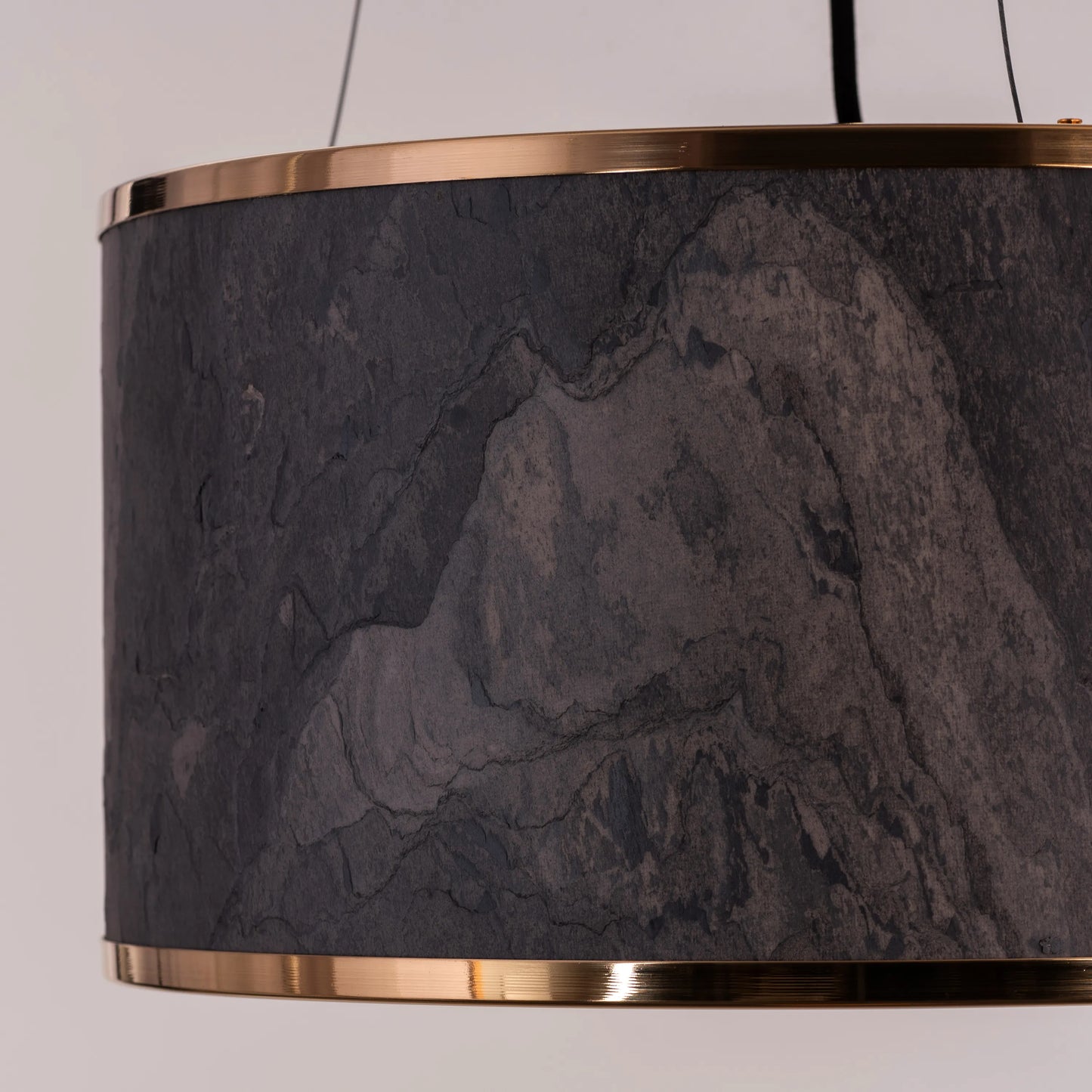 A contemporary pendant light named 'Touch & Glow,' featuring a striking gold stone veneer shade. The light's sleek design showcases the natural texture of the stone, beautifully reflecting and diffusing light to create a warm, inviting ambiance. This pendant light adds a touch of luxury and sophistication, making it an ideal choice for modern interiors.