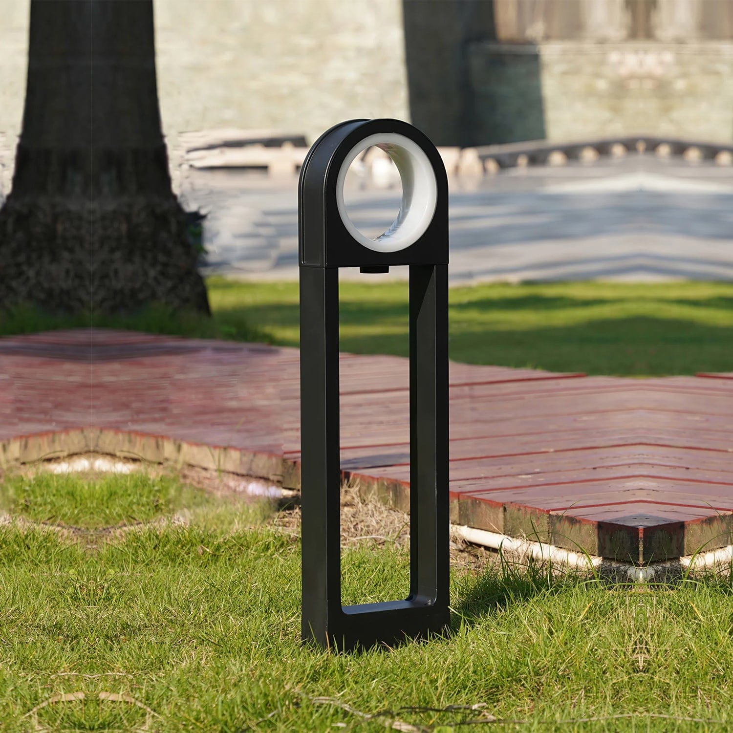 Luminara Guard Bollard Light casting warm glow on historic cobblestone street